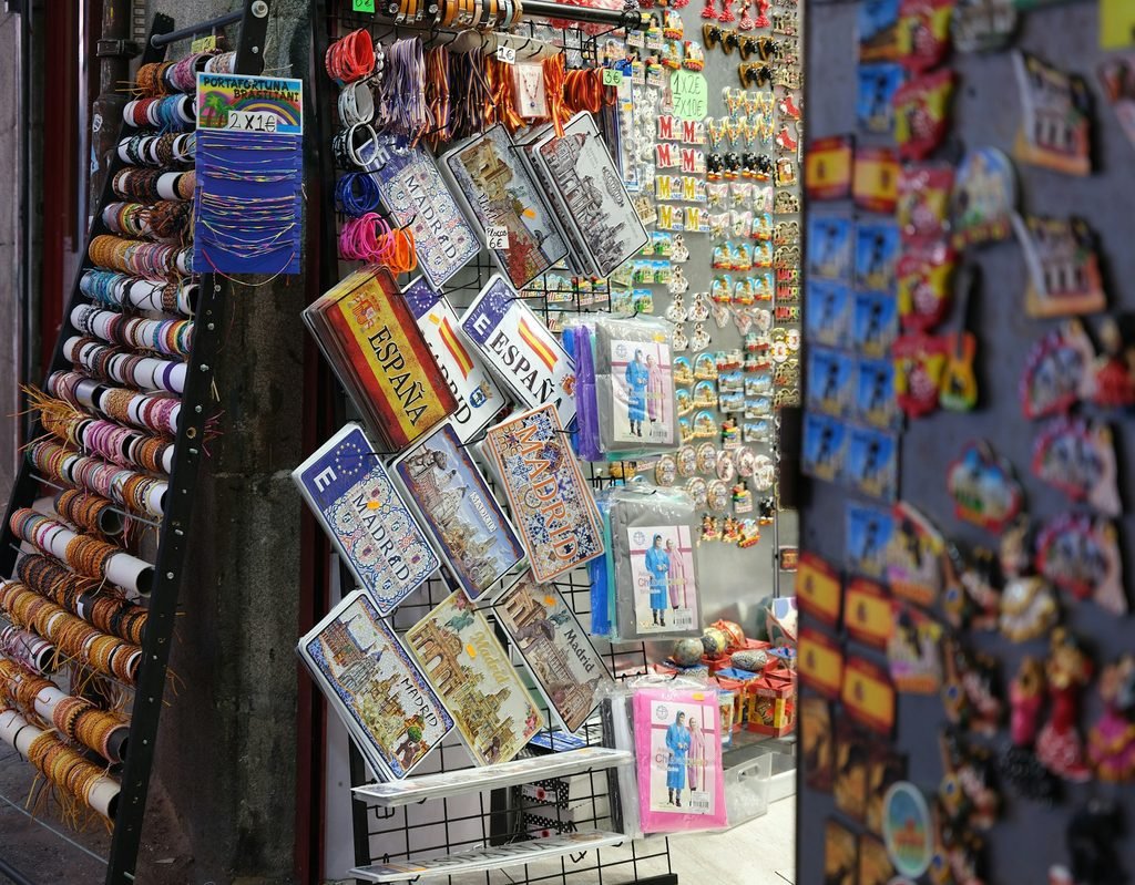Puesto de souvenirs con imanes y llaveros temáticos de España en una tienda.